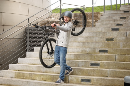 Jugendlicher trägt sein Hardtail eine lange Treppe herunter