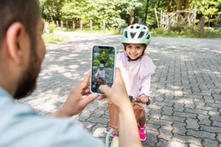 Papa fotografiert stolz seine Tochter auf einem Puky Laufrad